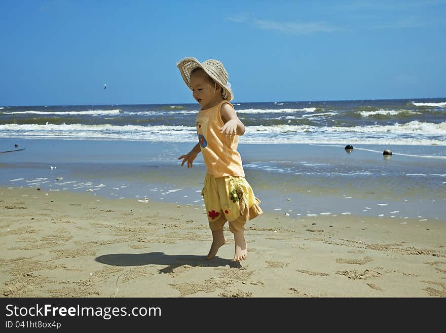 A child wearing a hat against the sea, jumping on the beach