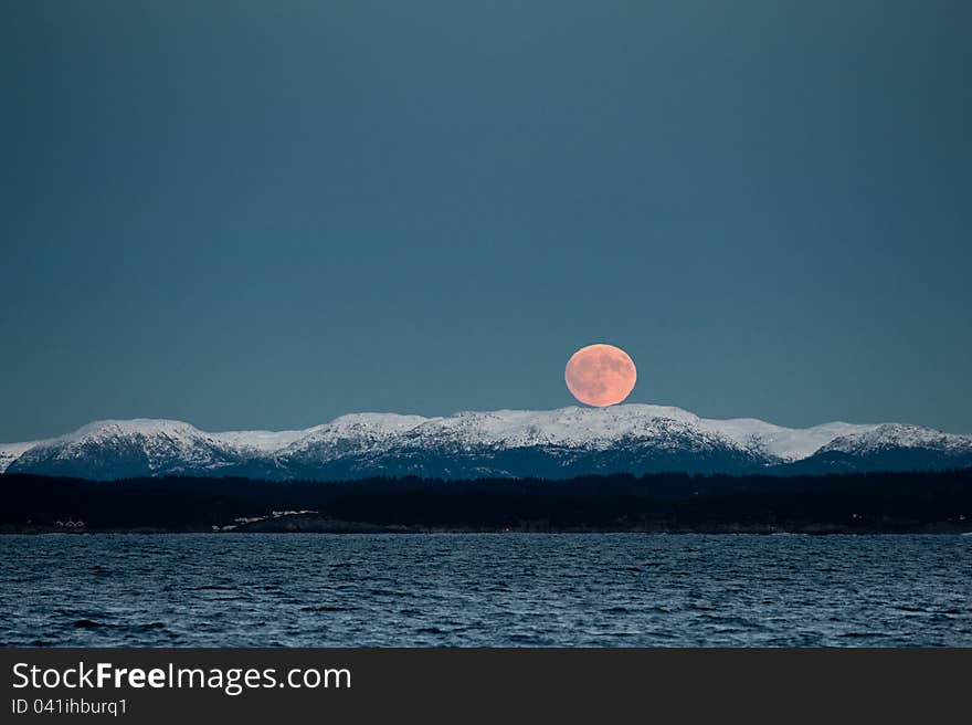 Rising red moon over the snowy Norwegian mountains. Rising red moon over the snowy Norwegian mountains