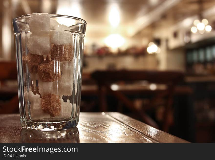 Cane and beet sugar in a glass beaker on a wooden table. Cane and beet sugar in a glass beaker on a wooden table