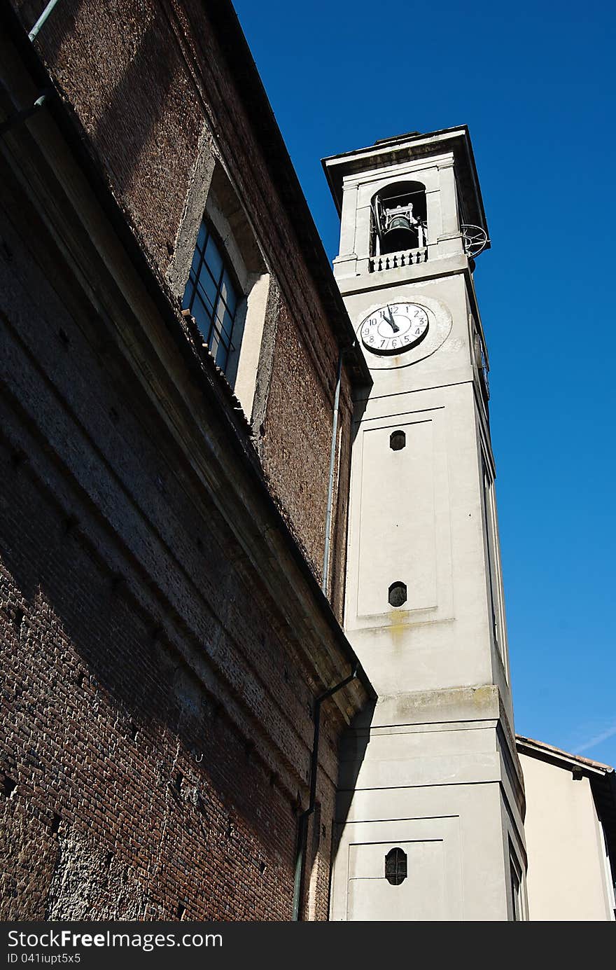 Italian imposing and old clock tower of Binasco church dramatic angle. Italian imposing and old clock tower of Binasco church dramatic angle