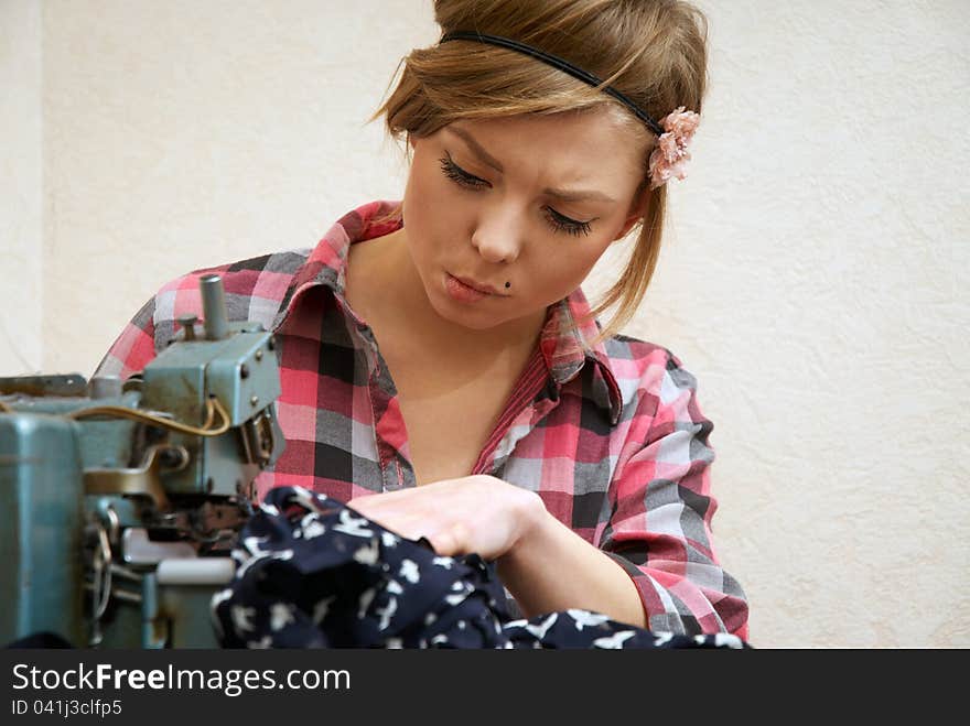 Woman seamstress posing near sewing machine