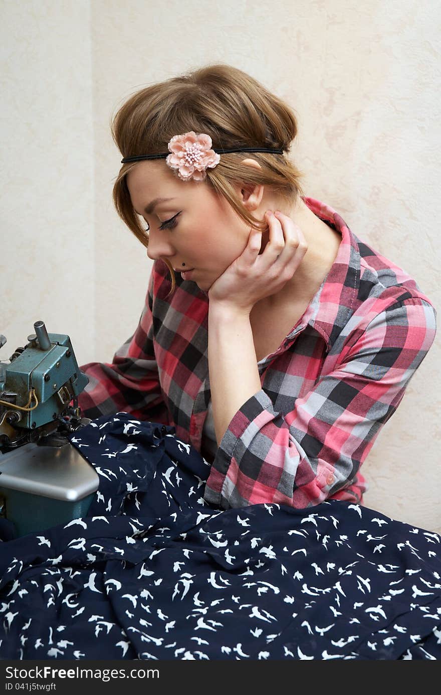 Woman seamstress posing near sewing machine