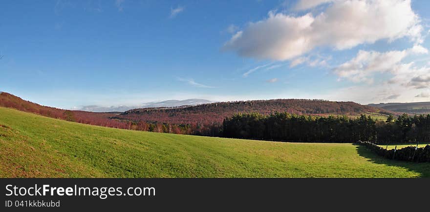 Wide view of purple heather hills with large blue sky and green grass. Wide view of purple heather hills with large blue sky and green grass