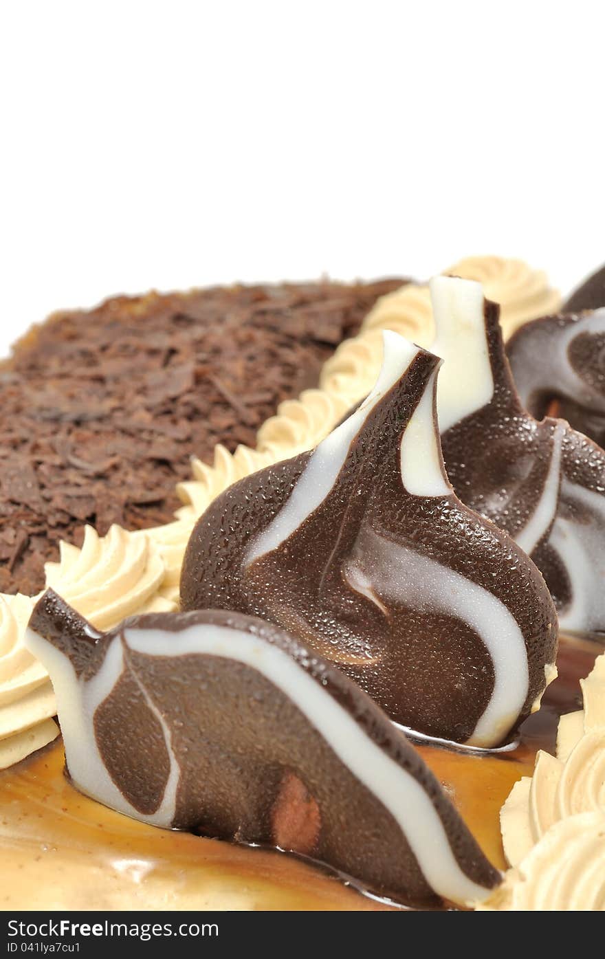 A delicious cake with grated chocolate, caramel and chocolate decorations against a white background. A delicious cake with grated chocolate, caramel and chocolate decorations against a white background