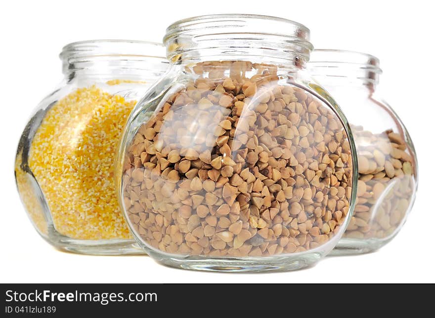 Glass jars with buckwheat, corn grits and lentils isolated on a white background