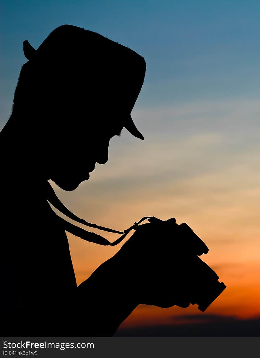 Photographer silhouette, staring at a camera review. Photographer silhouette, staring at a camera review.