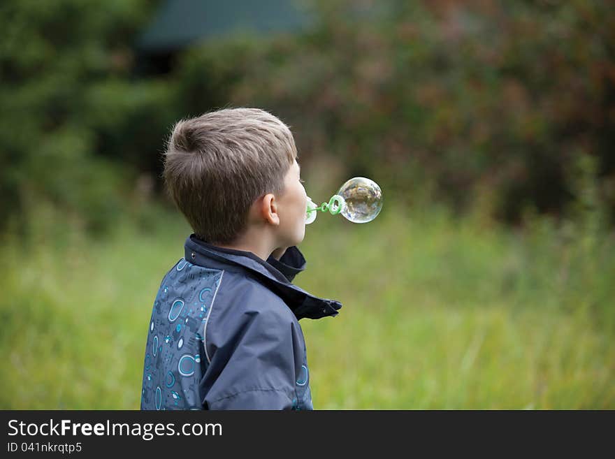 The boy starts up soap bubbles in countryside