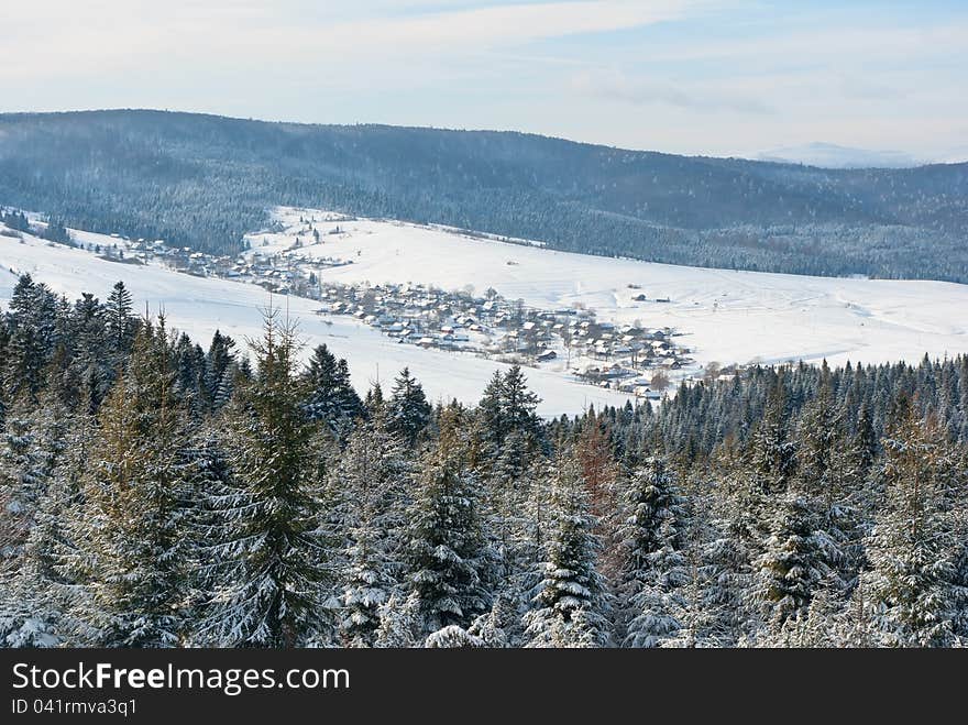 Village in valley between winter mountains