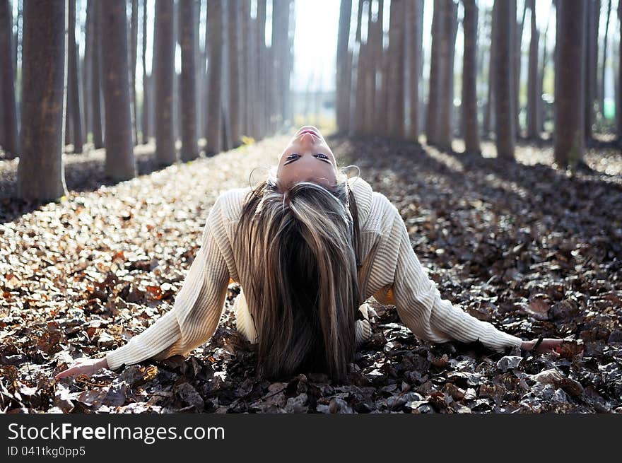 Beautiful blonde girl lying on leaves in a forest of poplars