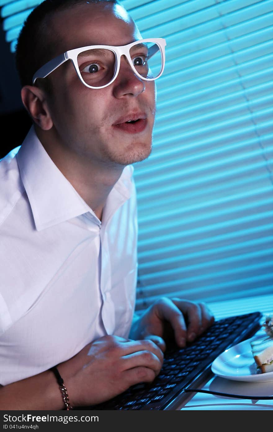 Funny nerd in glasses surfs internet at night time. Funny nerd in glasses surfs internet at night time