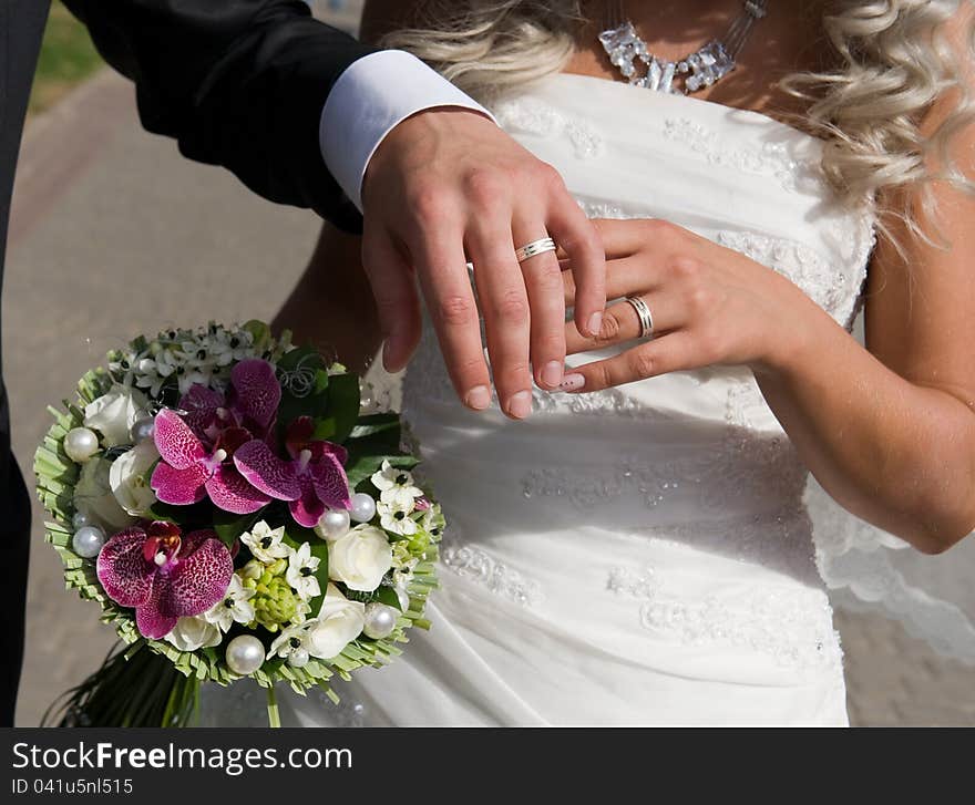 Portrait of two pairs of beautiful hands of bride and groom on the background of fabulous bouquet of flowers. Portrait of two pairs of beautiful hands of bride and groom on the background of fabulous bouquet of flowers