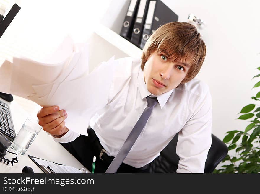 Angry businessman with documents in his office. Angry businessman with documents in his office