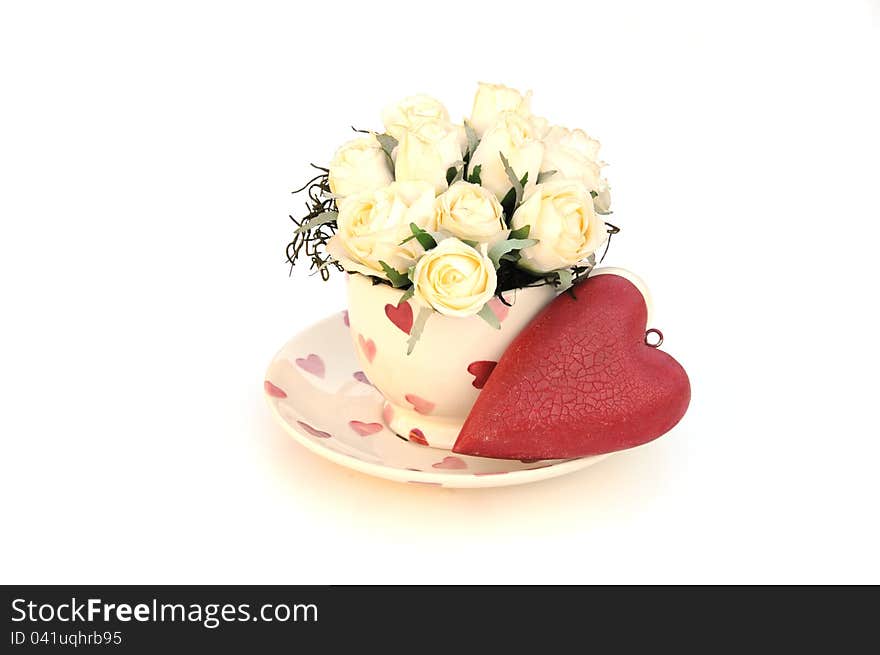 Pretty cream roses in a teacup and a red vintage love heart. Pretty cream roses in a teacup and a red vintage love heart