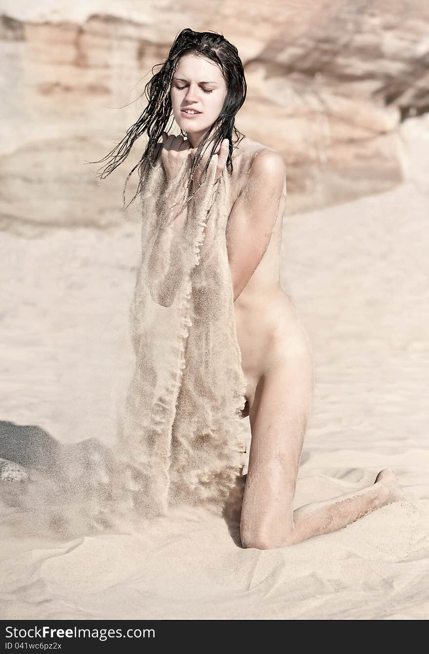 Nude woman playing with the sand