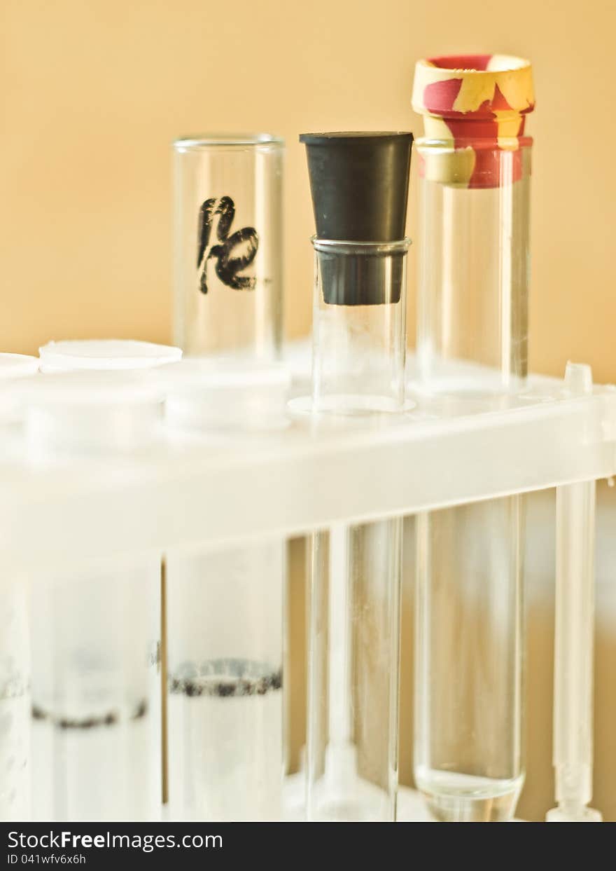 Glass and plastic vials in a plastic tripod stand on a yellow background. Glass and plastic vials in a plastic tripod stand on a yellow background