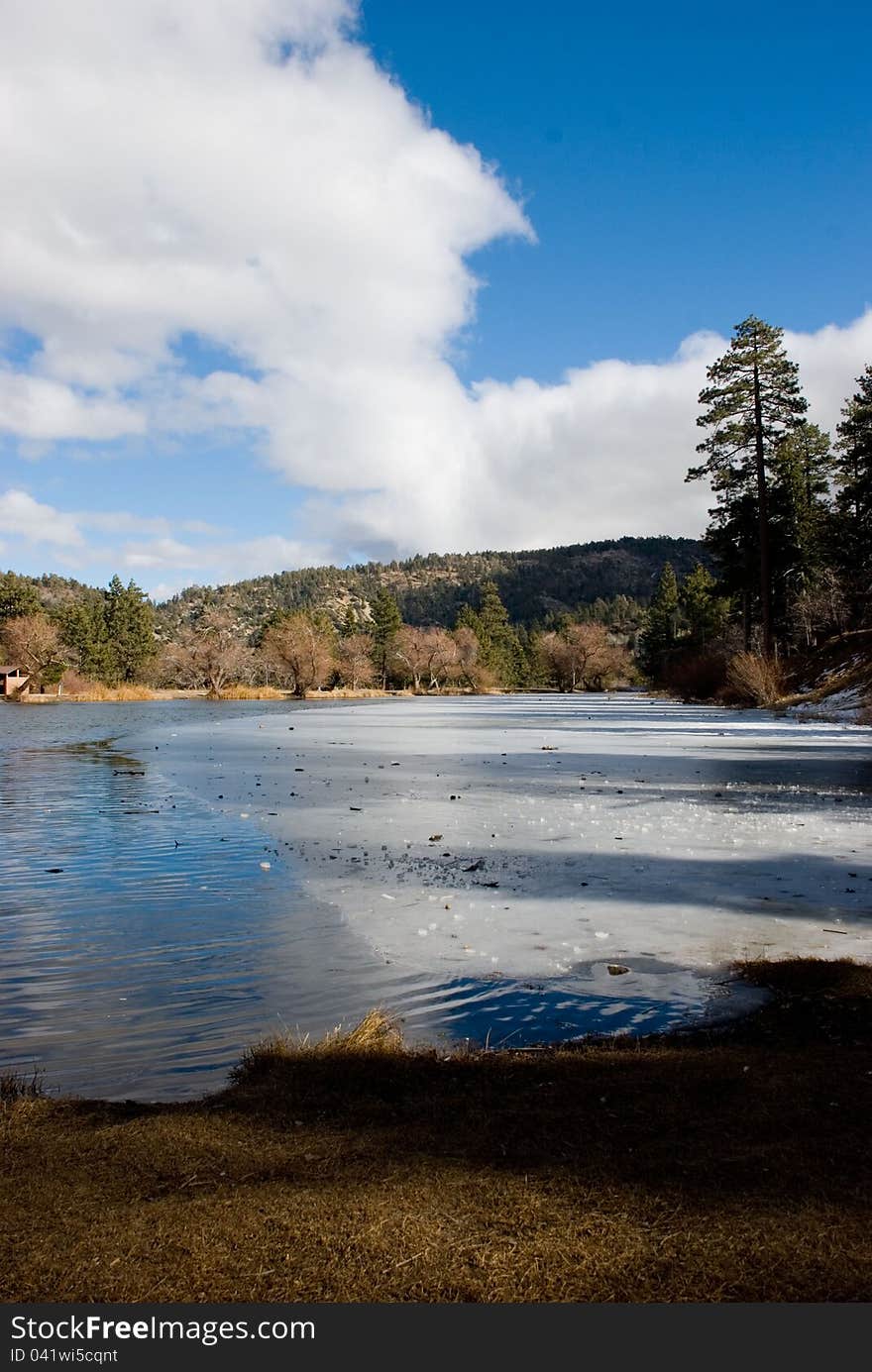 beautiful California Lake in the beginning of winter. Bright blue sky reflecting off the semi-frozen water of Jackson Lake in the San Bernardino National Forest. beautiful California Lake in the beginning of winter. Bright blue sky reflecting off the semi-frozen water of Jackson Lake in the San Bernardino National Forest.