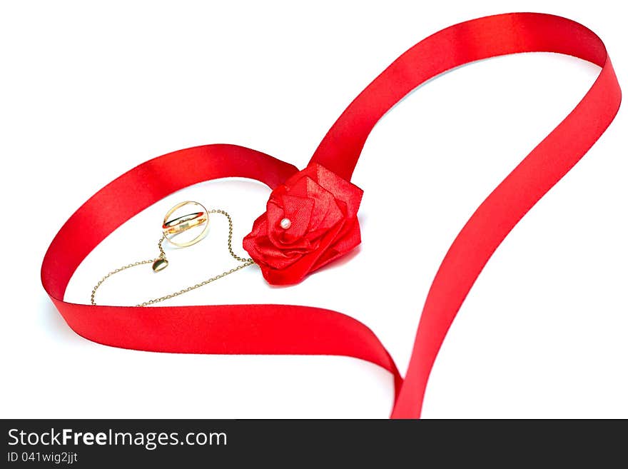 Golden wedding bands and chain with heart surrounded by red ribbon in heart shape with rose bow isolated on white. Golden wedding bands and chain with heart surrounded by red ribbon in heart shape with rose bow isolated on white