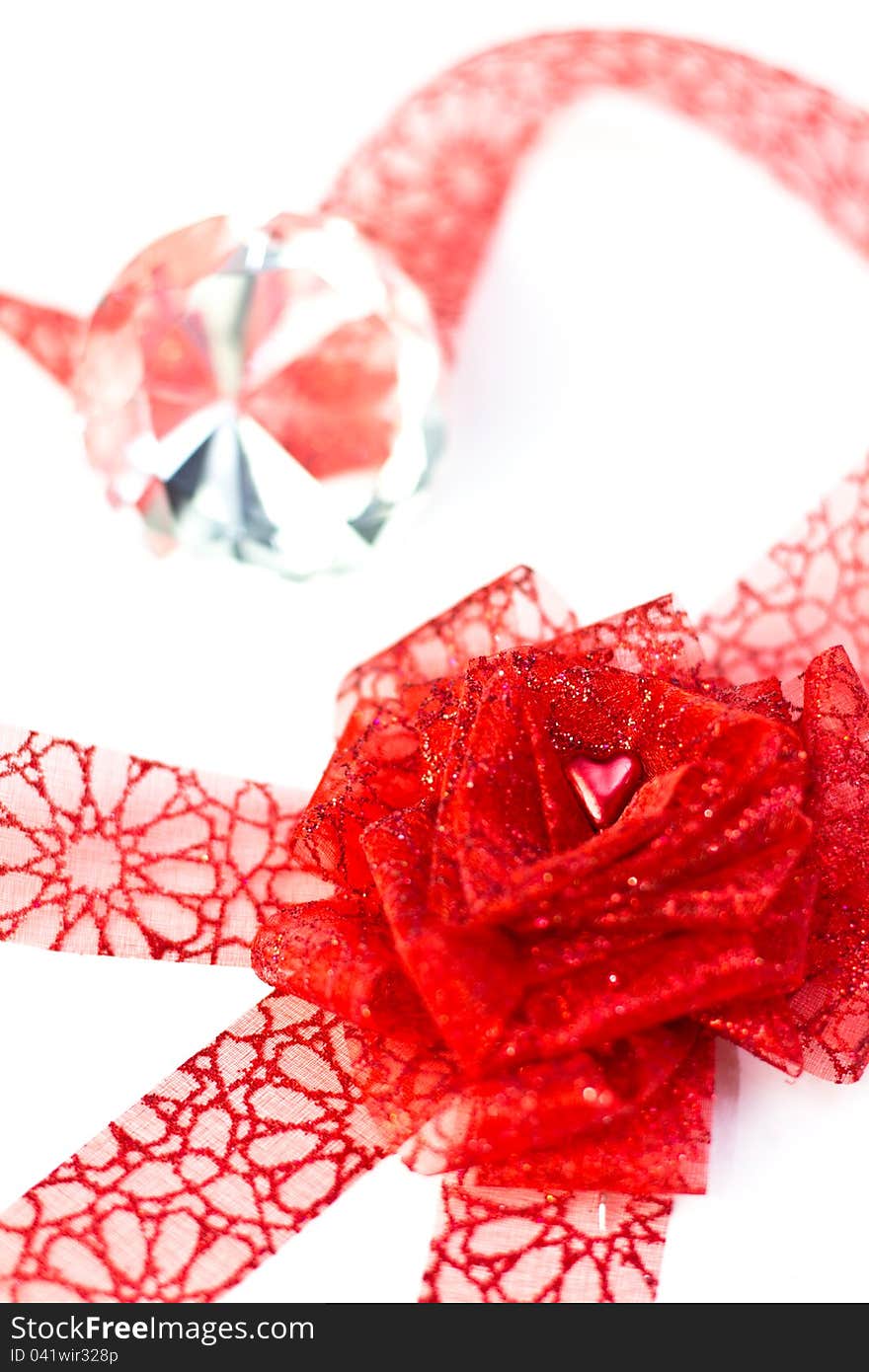 Heart in ribbon forming a rose in front of diamond on white background. Shallow depth of field. Heart in ribbon forming a rose in front of diamond on white background. Shallow depth of field.