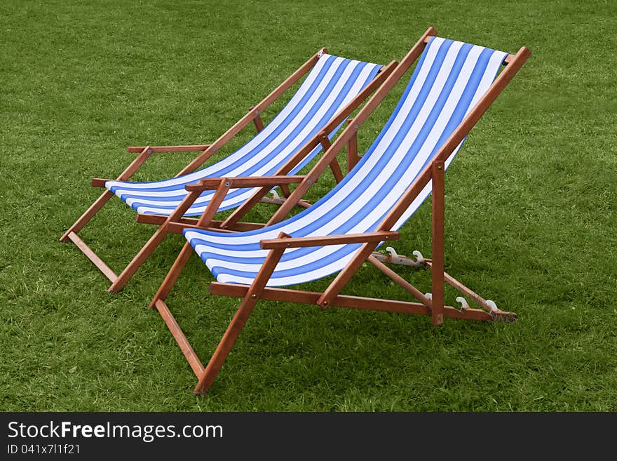 Two chaise lounges standing on the green grass. Two chaise lounges standing on the green grass