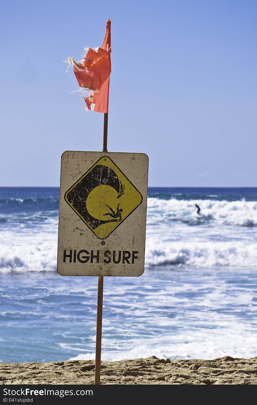 High surf danger sign with surfer in background