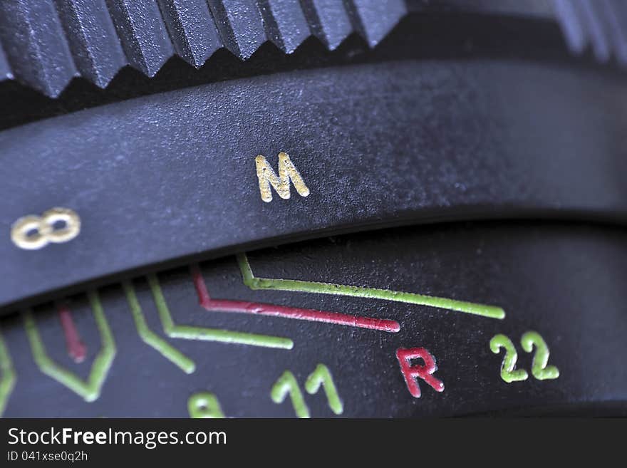 Closeup of vintage photo-camera lens; selective focus on M letter. Closeup of vintage photo-camera lens; selective focus on M letter