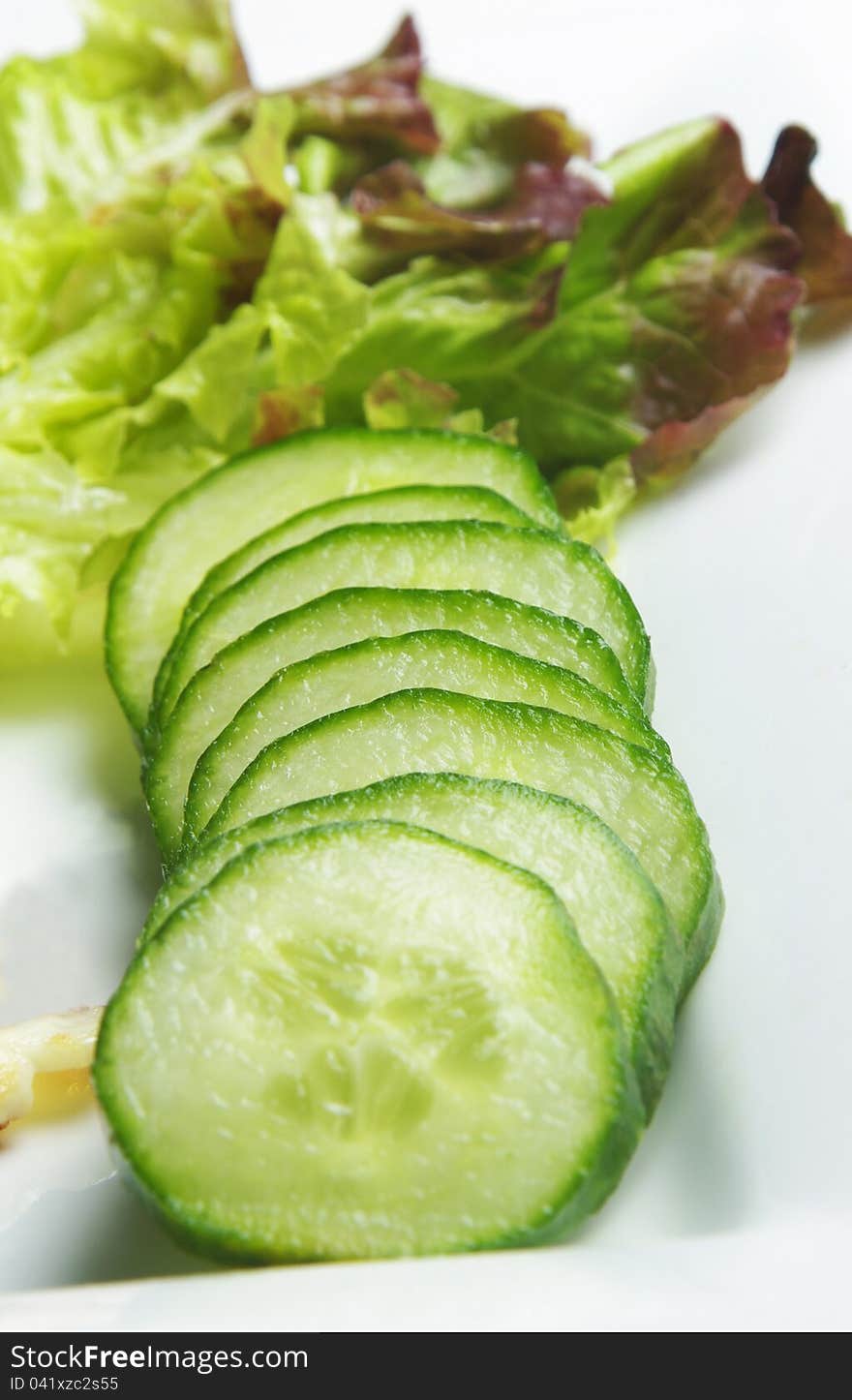 Cucumbers on plate with green salad. selective focus