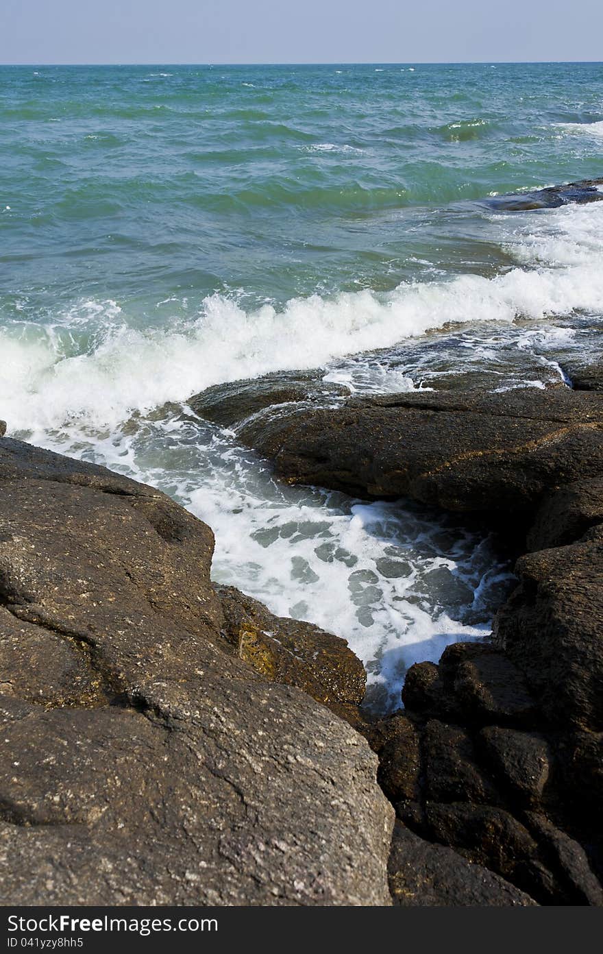 Wave of sea pass through crack of stone beach