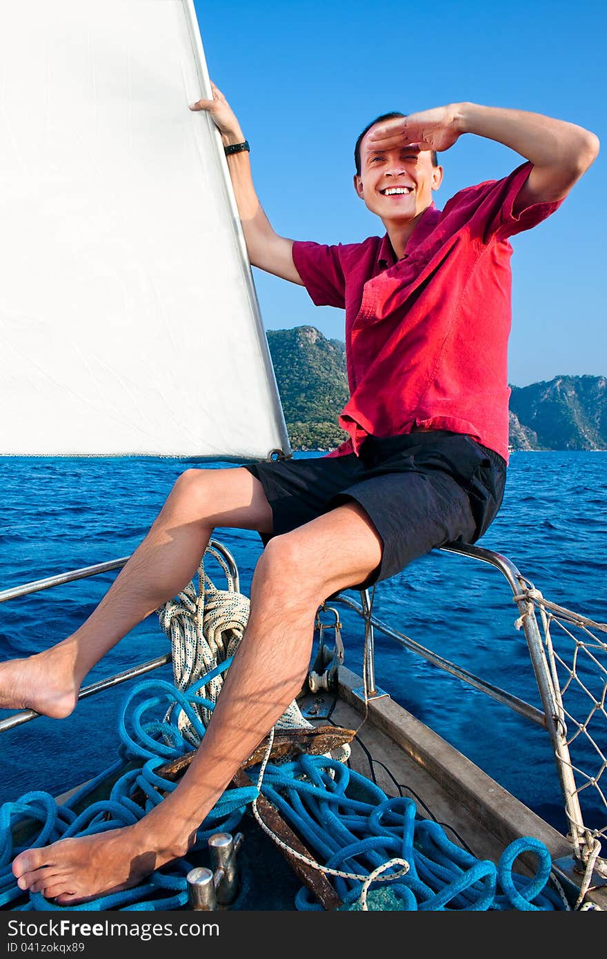 Smiling young man on the yacht looks afar