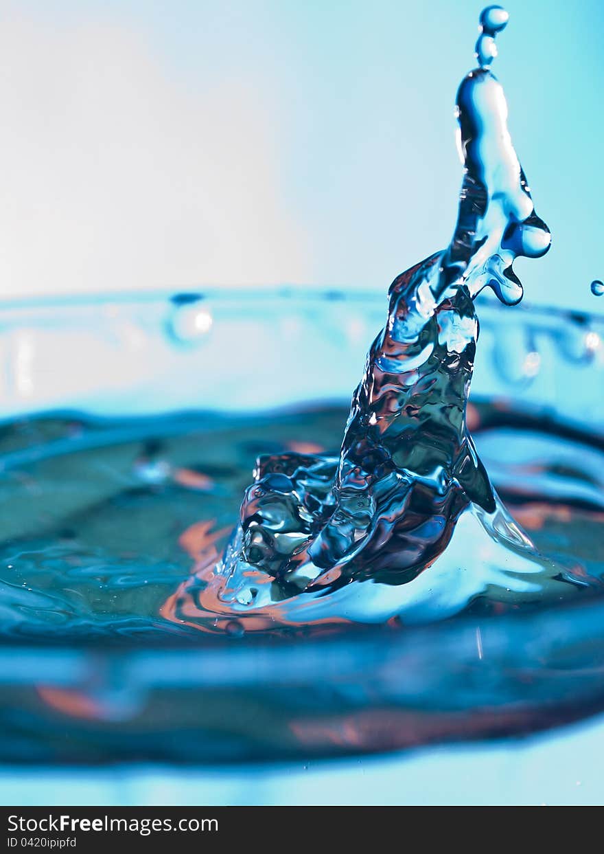 Droplet falling in the glass of blue water