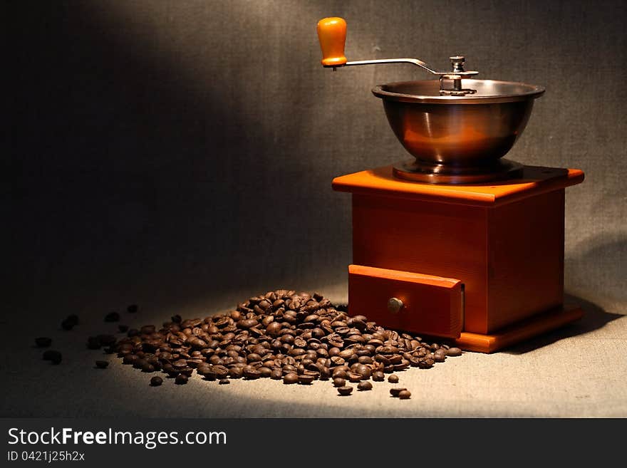 Nice vintage manual coffee grinder near beans on canvas background. Nice vintage manual coffee grinder near beans on canvas background