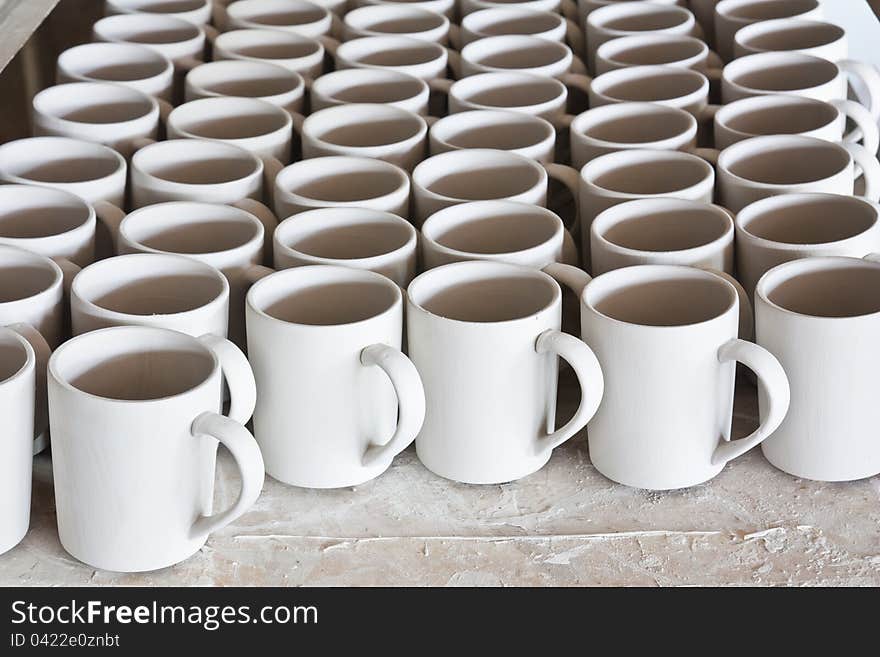 Ceramic mugs in racks in ceramic work shop