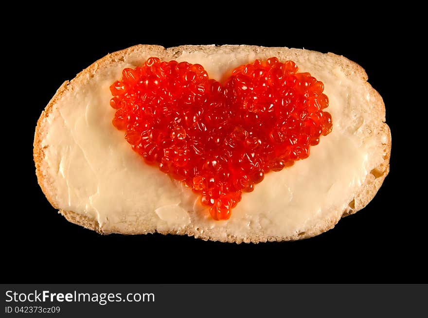 Heart made of red caviar on bred and butter isolated on black. Heart made of red caviar on bred and butter isolated on black