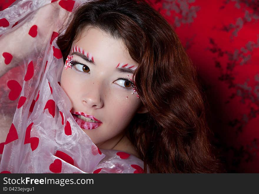 Sexy woman with candy makeup  in a red dress holding heart shaped fabric. Sexy woman with candy makeup  in a red dress holding heart shaped fabric