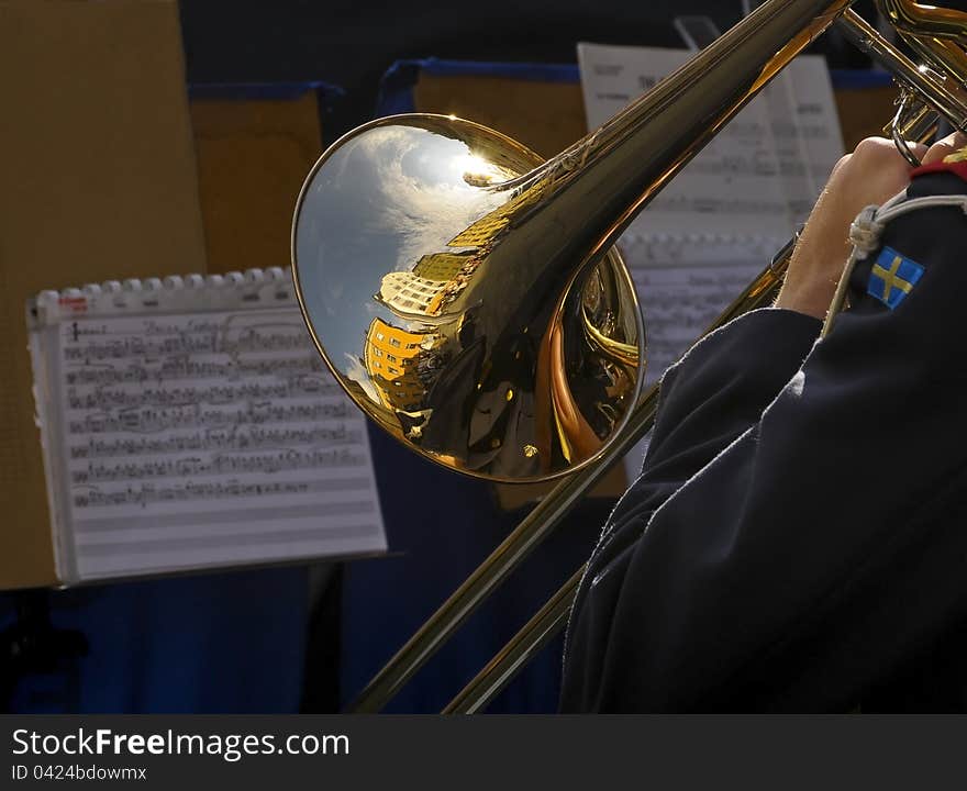 Swedish soldier playing trombone on the military parade. Reflection of Stockholm's houses at trombone surface