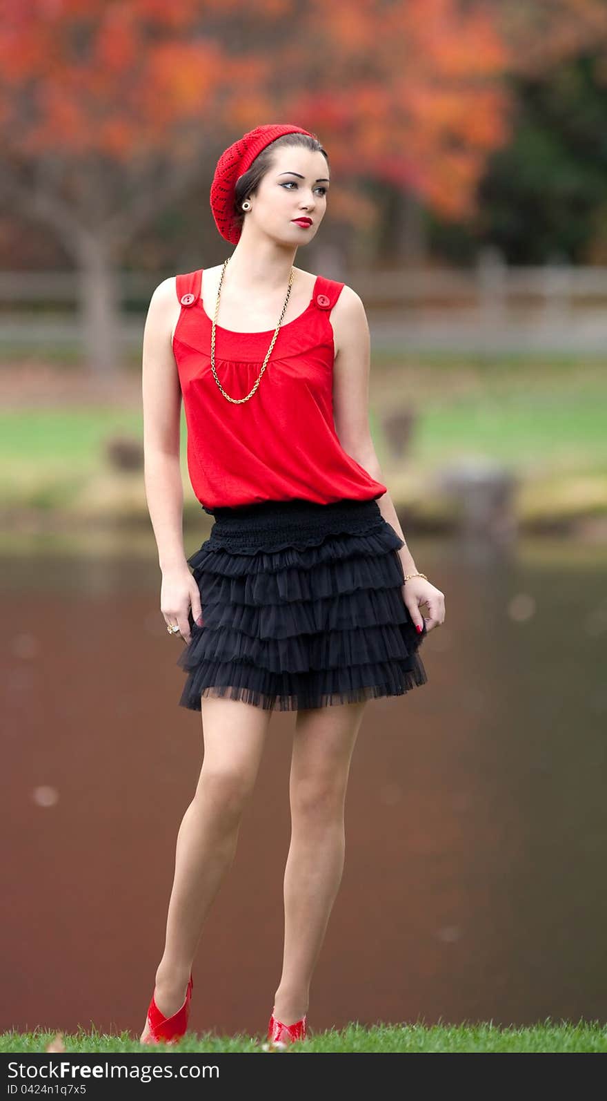 A portrait of a pretty young woman in a fashionable outfit, standing by a lake in the fall. A portrait of a pretty young woman in a fashionable outfit, standing by a lake in the fall