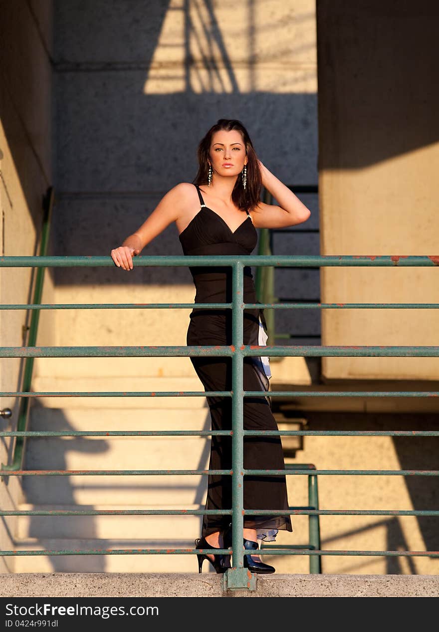 A portrait of a beautiful, elegantly dressed woman outdoors on set of stairs on a downtown parking garage. A portrait of a beautiful, elegantly dressed woman outdoors on set of stairs on a downtown parking garage