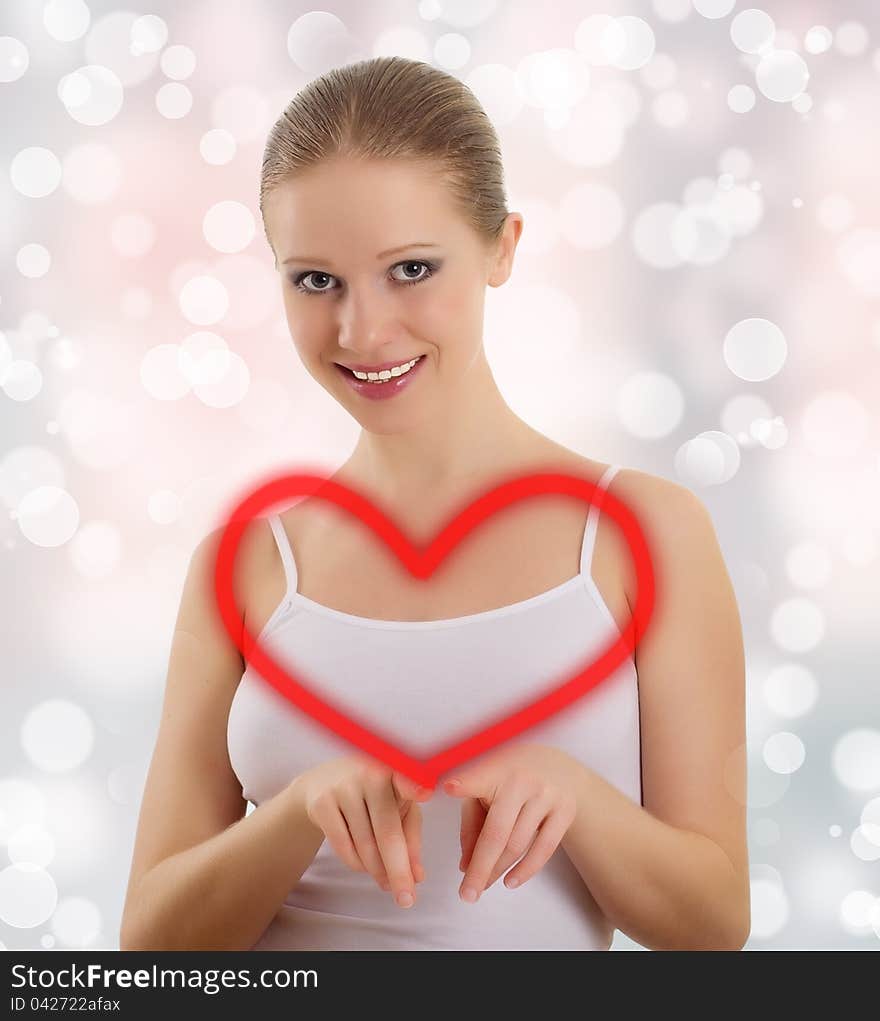 Beautiful young woman draws a big red heart on an abstract background