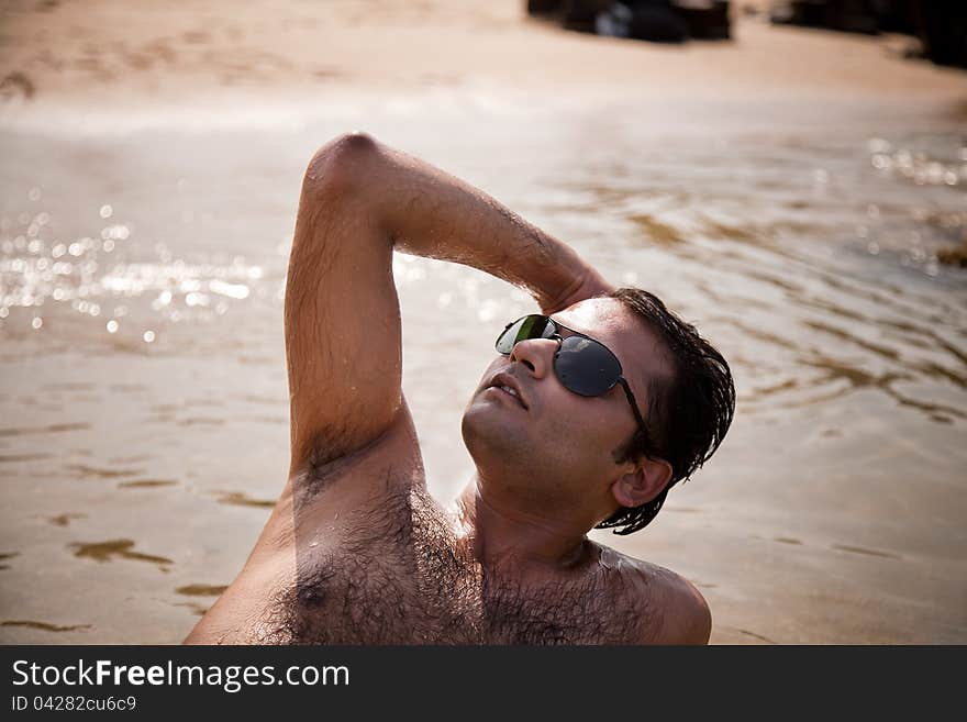 Indian man swimming at ocean beach with sunglasses