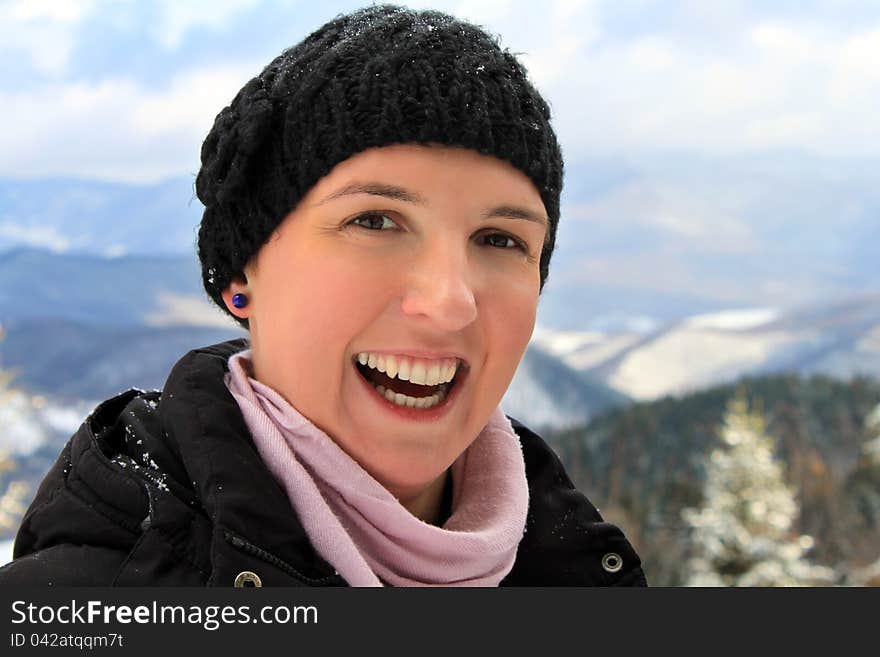 Happy young woman with a big smile on her face, spending her winter holiday in a mountain cabin, happiness concept