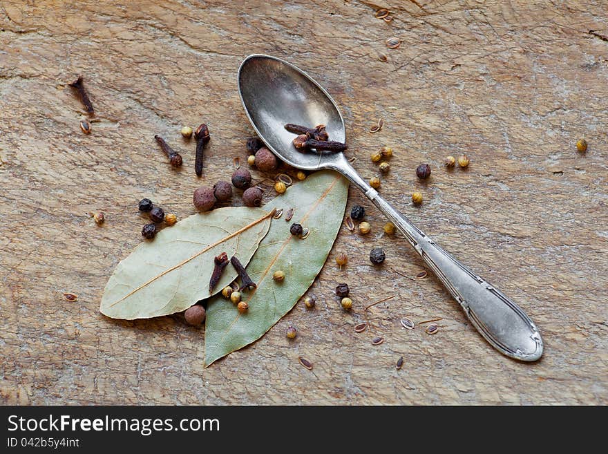 Spices and spoon on a wooden board.