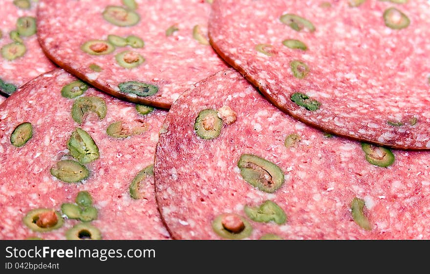 Salame slices with green olives closeup