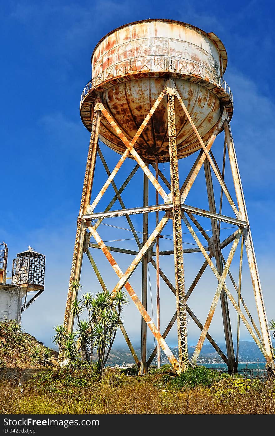 Rusty water tank tower on blue sky background