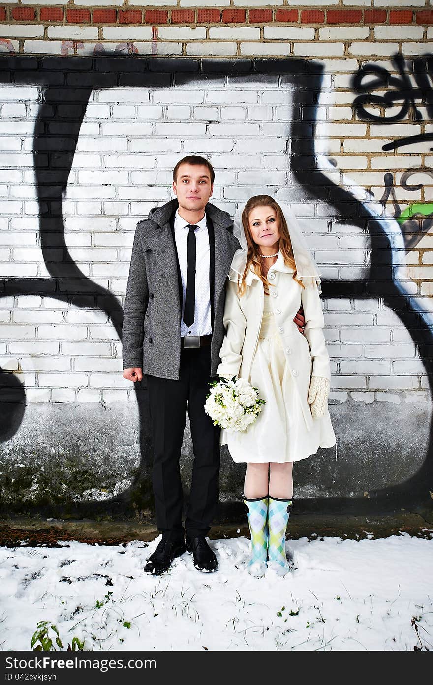 Happy bride and groom against a wall with graffiti