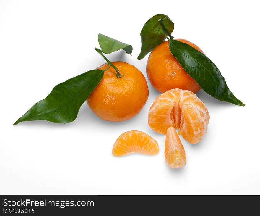 Fruits of a tangerine with a thin skin and without a thin skin with green leaves on a white background. Fruits of a tangerine with a thin skin and without a thin skin with green leaves on a white background.