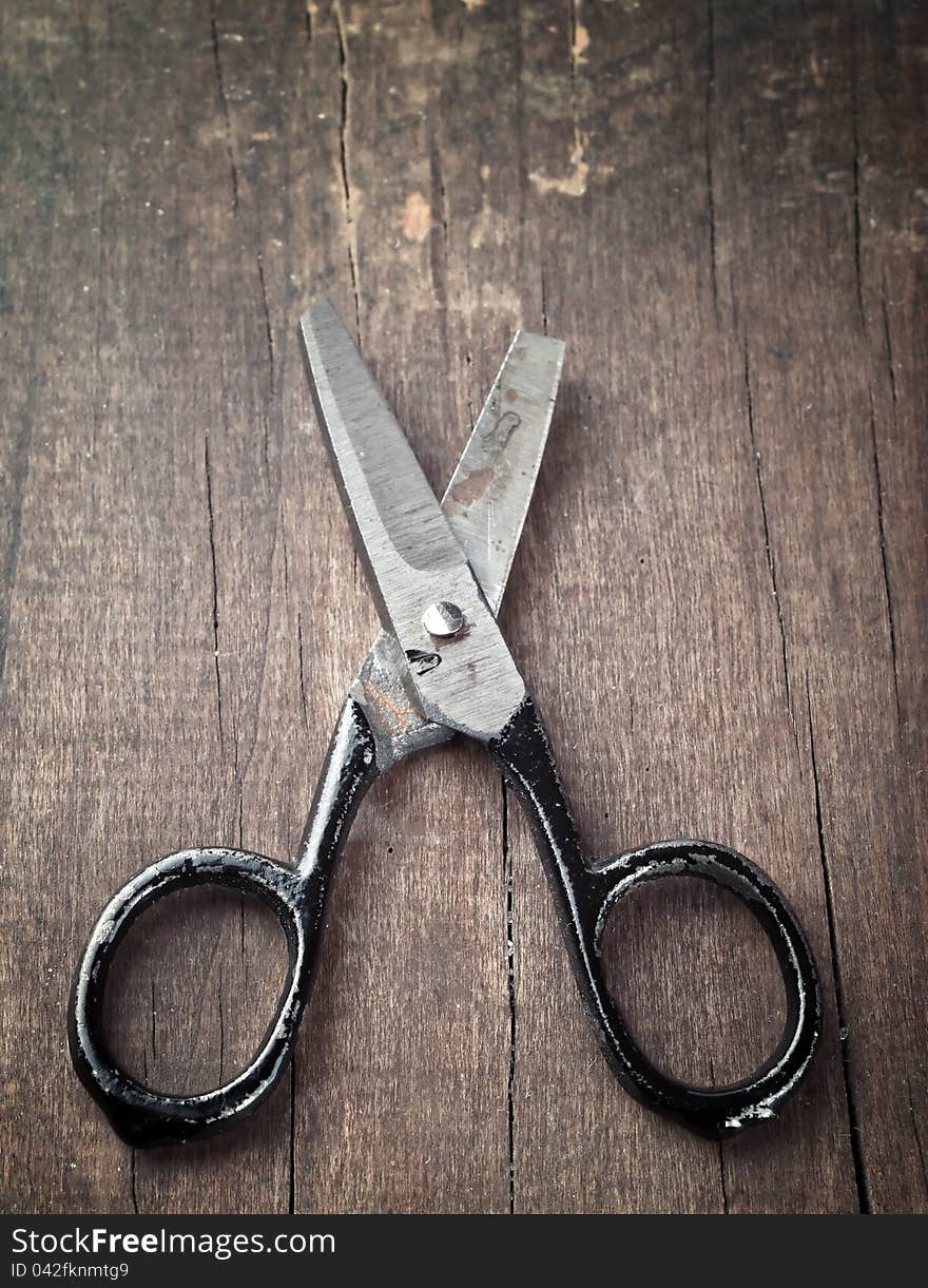 Old broken scissors on old plank