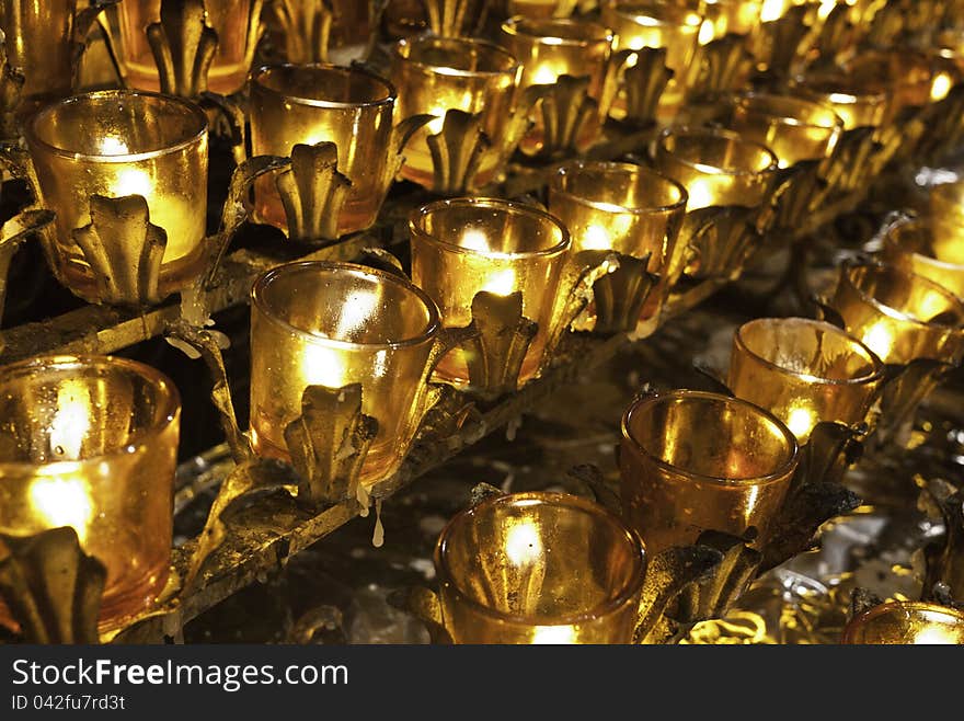 Rows of lit prayer candles in a Catholic church.