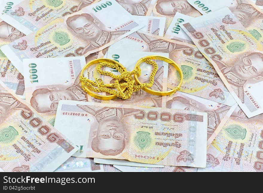 Gold chain an gold bracelet placed up to Thai money background. Gold chain an gold bracelet placed up to Thai money background.