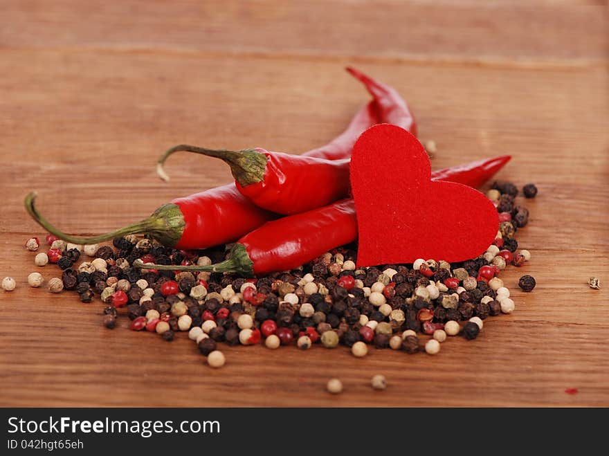 Red hot chili peppers with heart shape over wooden background. Red hot chili peppers with heart shape over wooden background