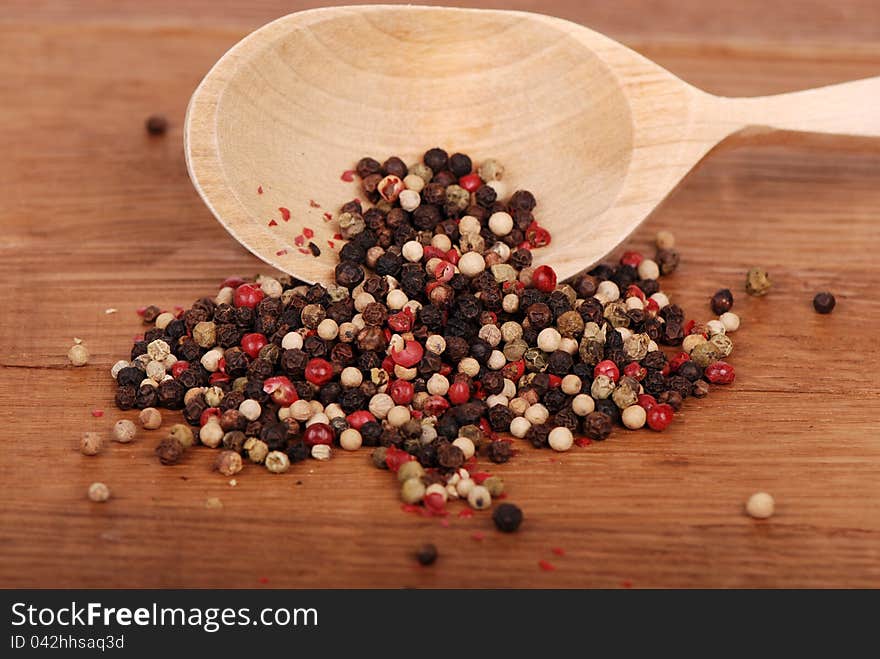 Studio shot of white, red and black ground peppers with new spoon on old wooden background/