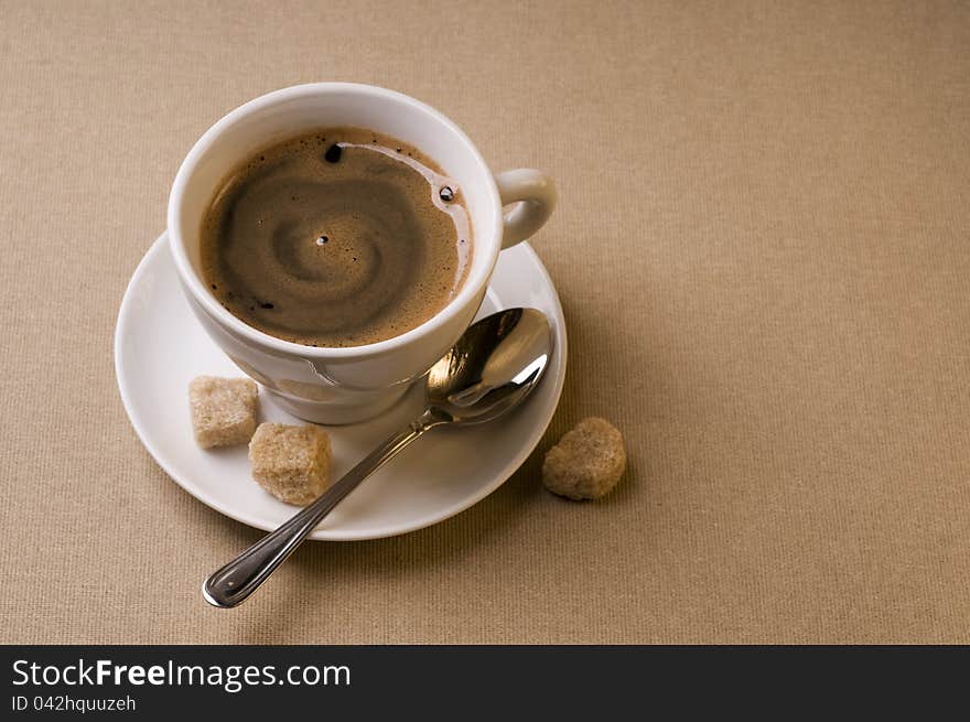 Black coffee cup with brown sugar over textured background